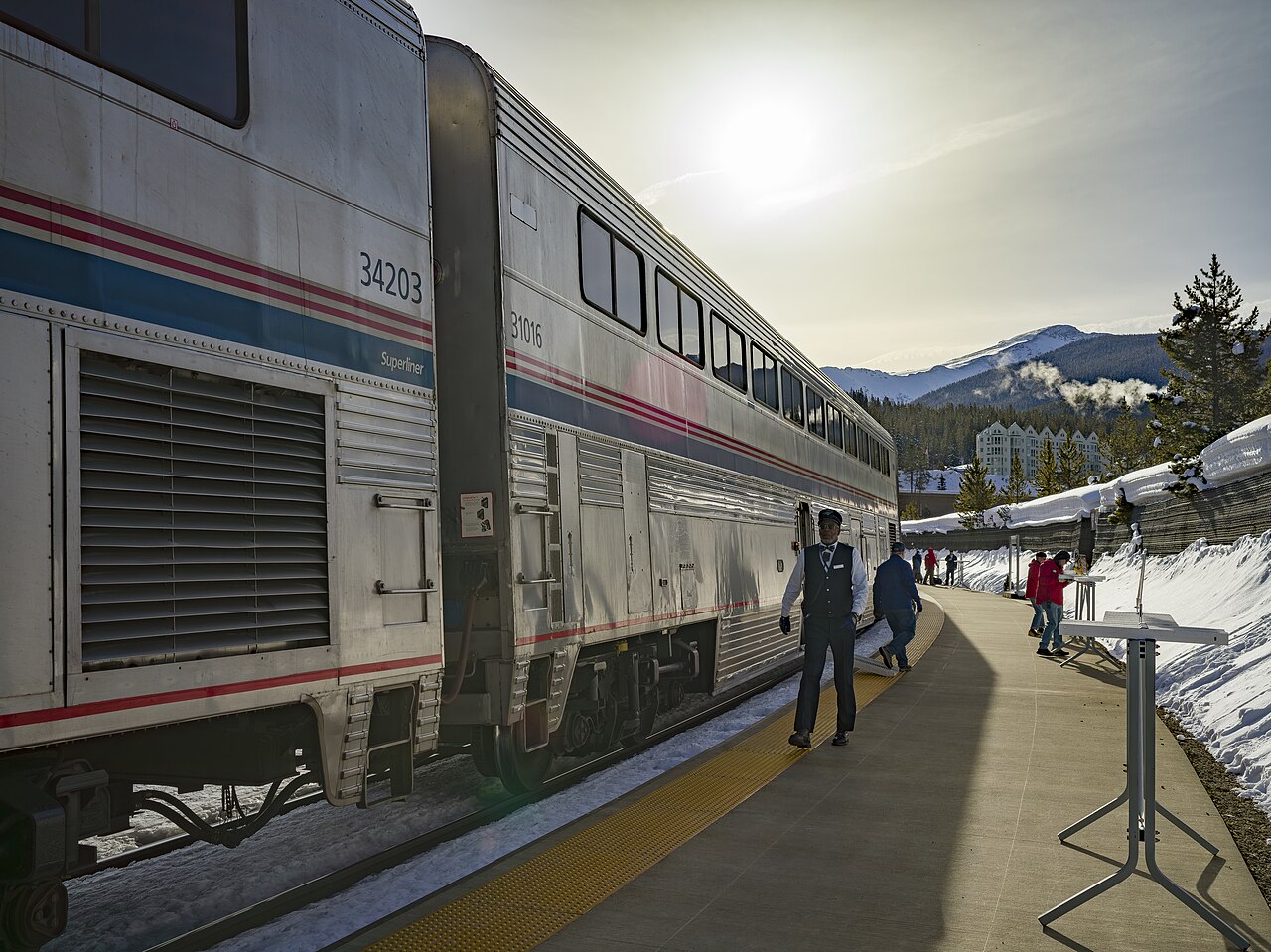 Amtrak Winter Park Express train at the Winter Park Resort station platform, with snow and mountains behind