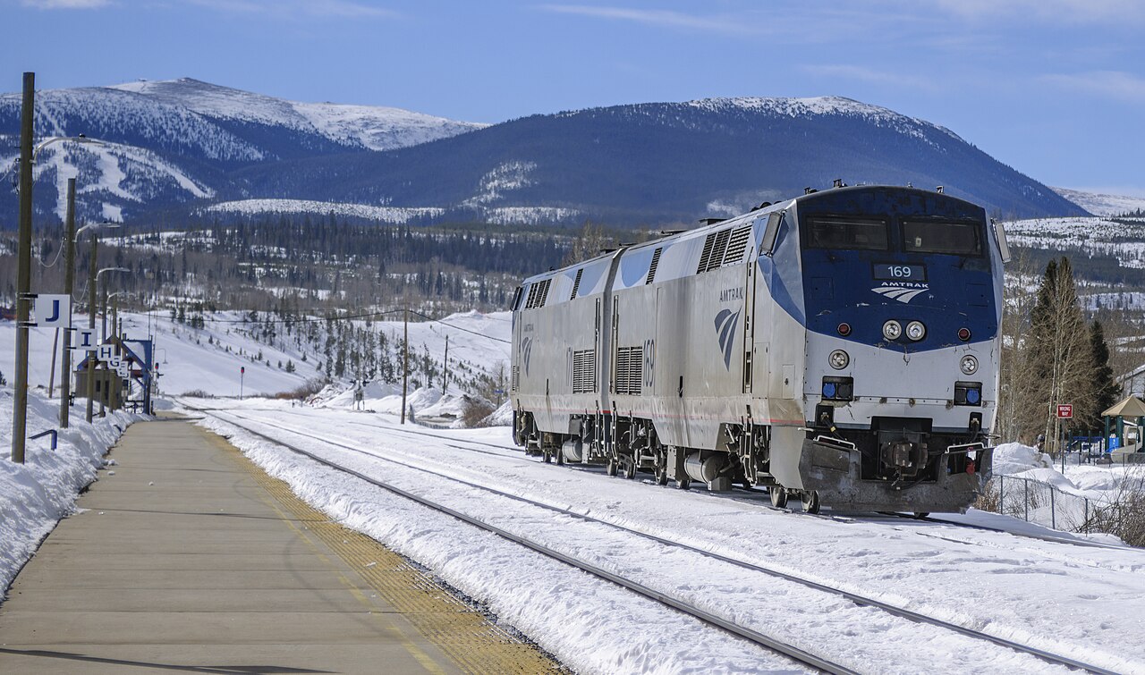 Amtrak locomotives for the Winter Park Express on snowy tracks at Winter Park, with ski runs on the mountains behind